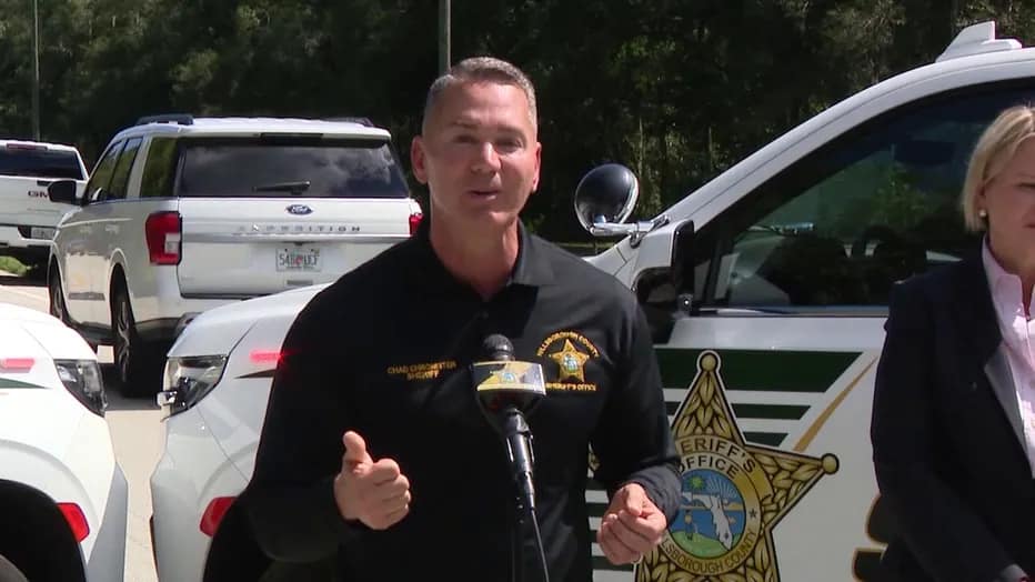 A man in sheriff's uniform standing behind a microphone