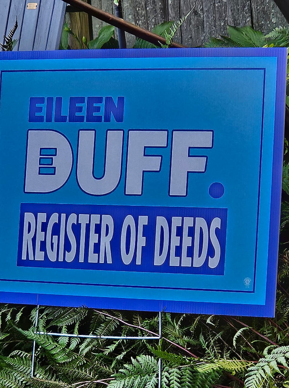 A lawn sign in mid-blue with the words EILEEN DUFF FOR REGISTER OF DEEDS